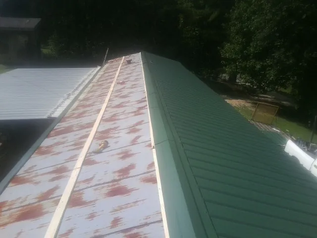 Old rusted panels beside newly installed green metal roofing — Wind Damage Roof Repair by Roofing Brothers in North Oxford