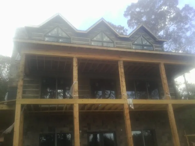 Dormers and porch framing on a large log home under construction — Roof Coating work by our crew in North Oxford