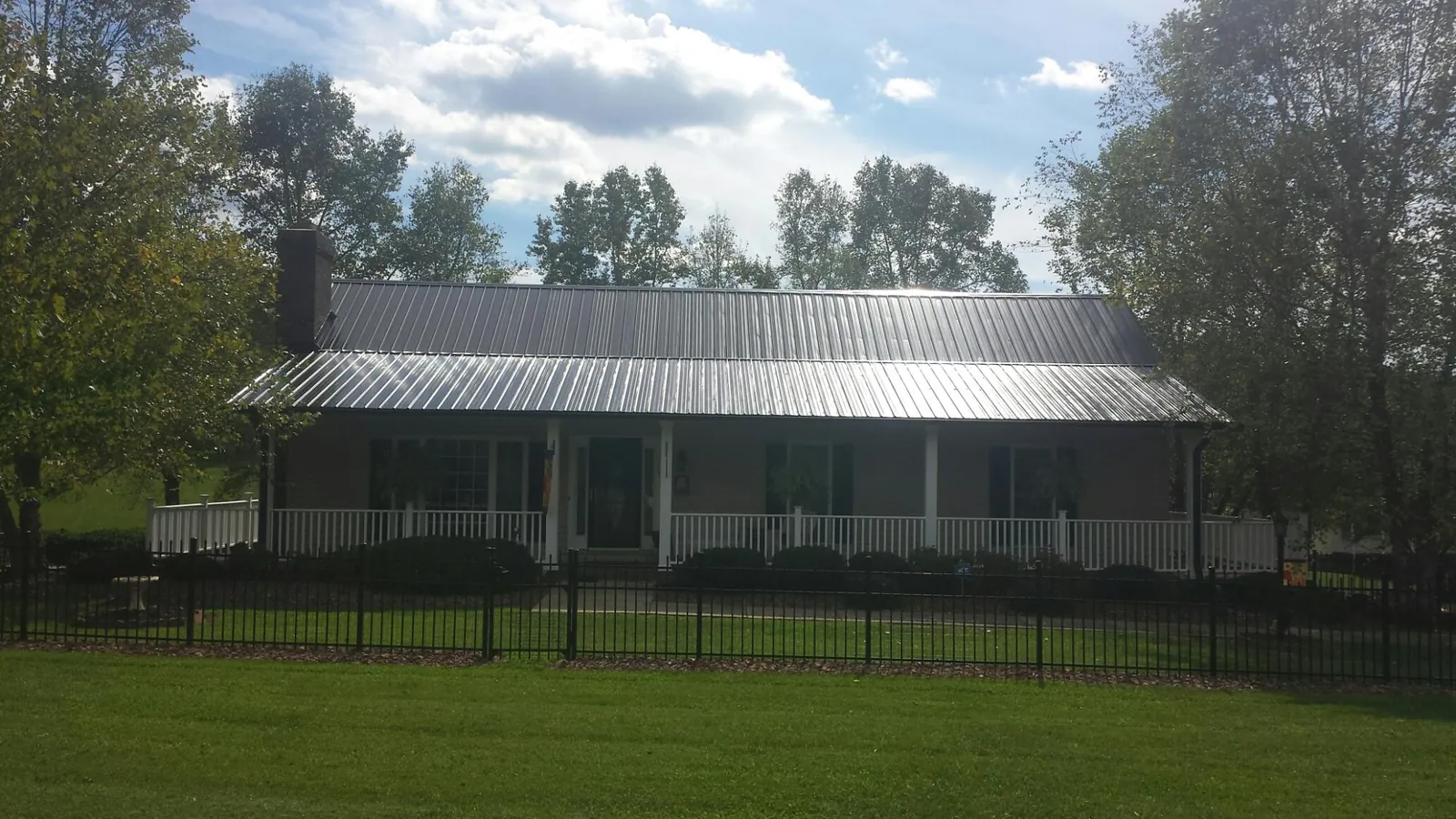 Gray metal roof on a brick ranch with a full width front porch — Gutter Guard Installation work by our crew in North Oxford