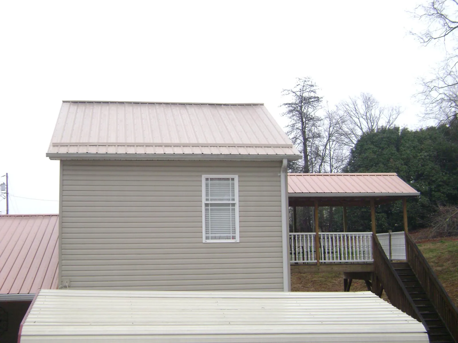 Tan metal roofs on a two story addition and attached porch, from a Roof Replacement job in North Oxford